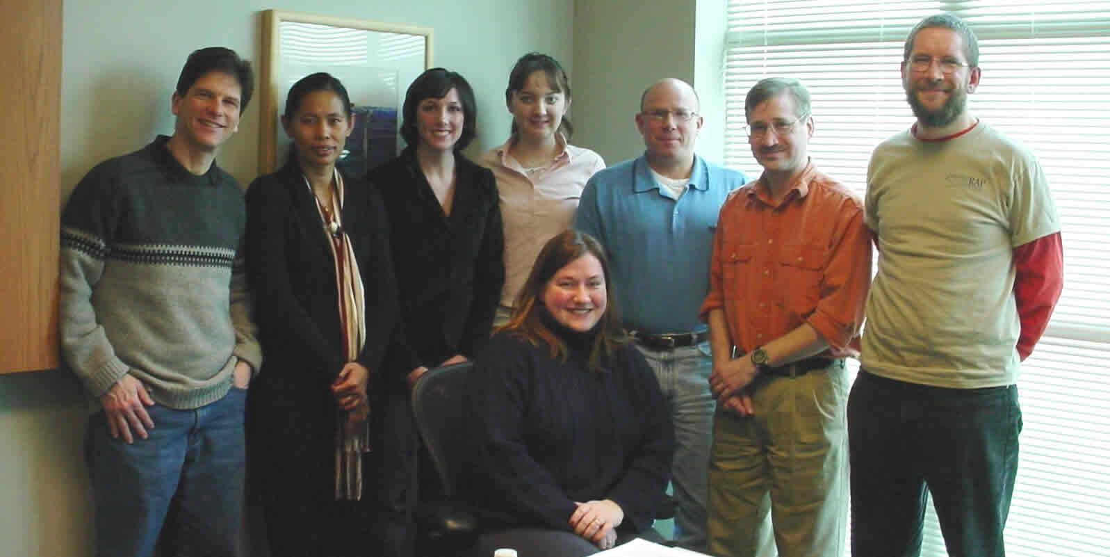 A group of eight people stand and sit for a team photo.